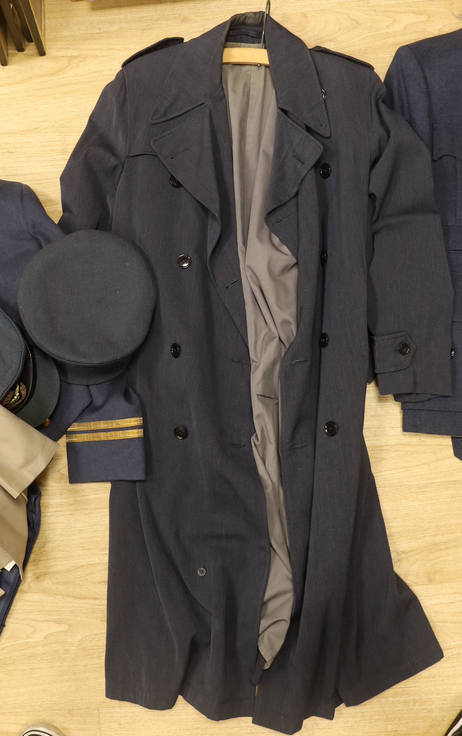 A collection of post-war RAF uniforms, comprising; two caps, double-breasted overcoat, dress uniform of jacket, trousers and gloves, two sets of jacket and trousers with ribbons for WWII awards, plus a pair of navigator’